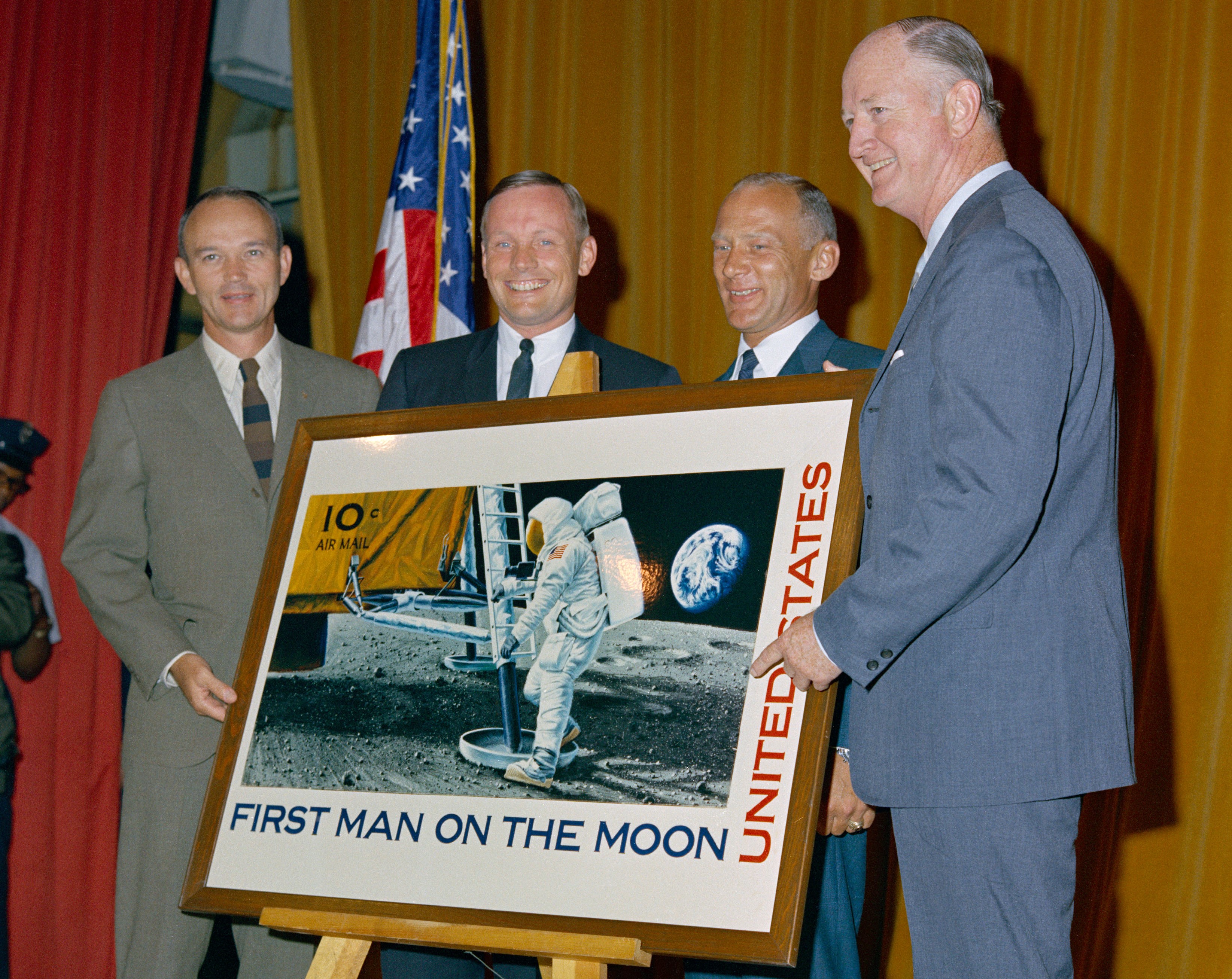 Apollo 11 astronauts Michael Collins, left, Neil A. Armstrong, and Edwin E. “Buzz” Aldrin with Postmaster General Winton M. Blount display an enlargement of the stamp commemorating the first Moon landing