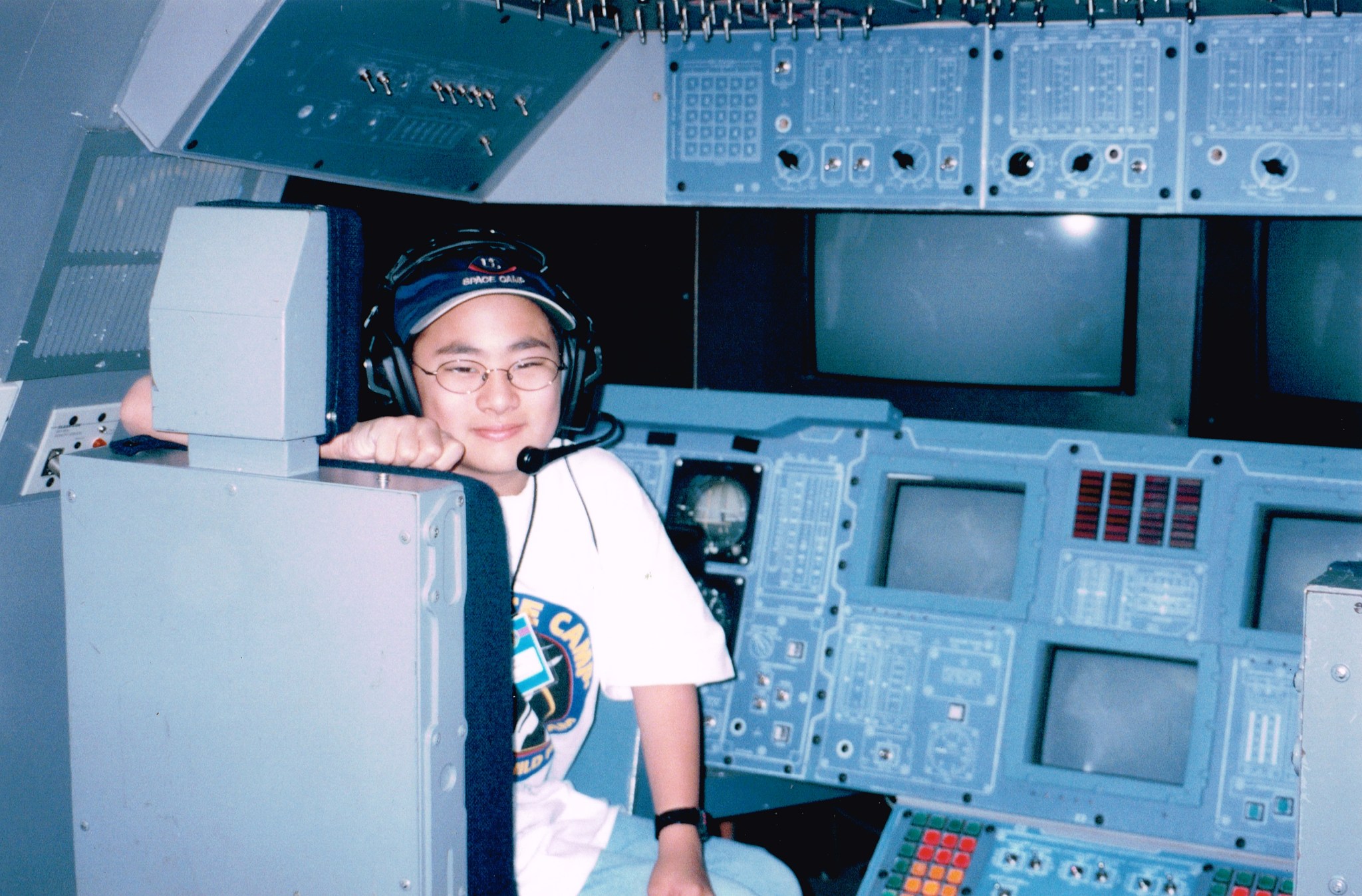 A young Kyle Helson sits in front of a control panel wearing a headset at space camp.