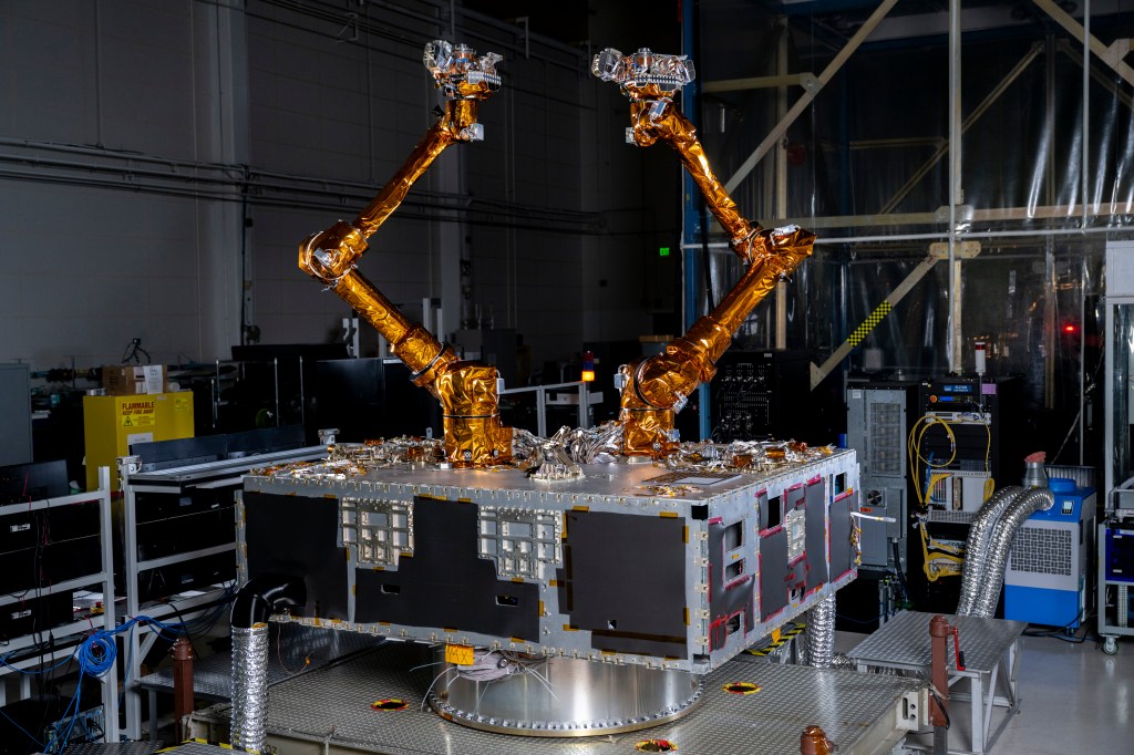 Two robotic arms wrapped in gold material sitting on top of a black and silver box.