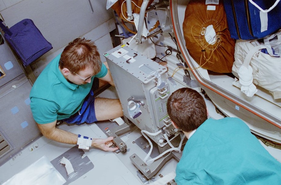 Steven L. Smith, left, and Peter J.K. “Jeff” Wisoff set up the bicycle ergometer in the shuttle’s middeck