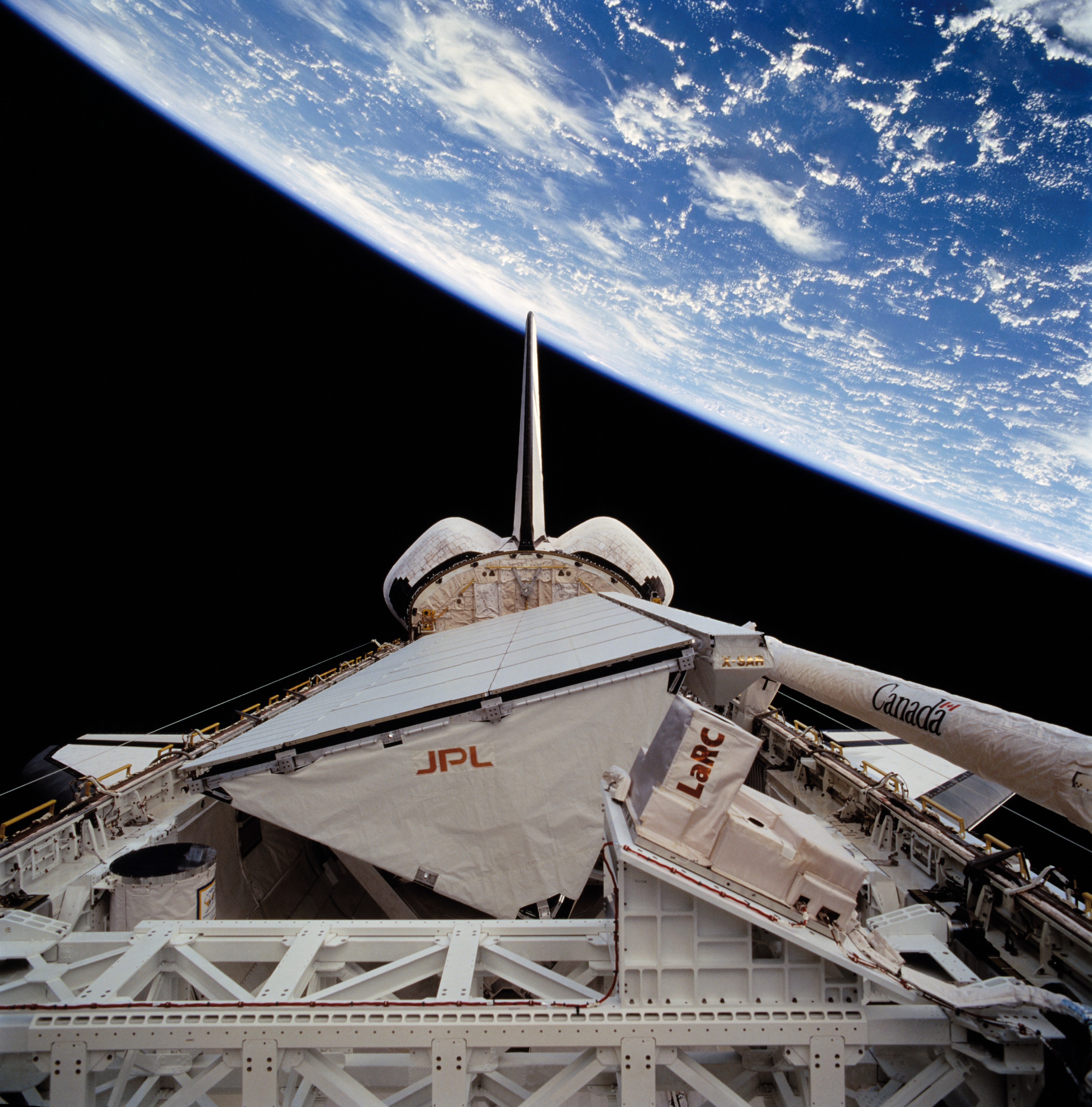 The Space Radar Laboratory-2 payload in Endeavour’s cargo bay, showing SIR-C (with the JPL logo on it), X-SAR (the long bar atop SIR-C), and MAPS (with the LaRC logo on it)