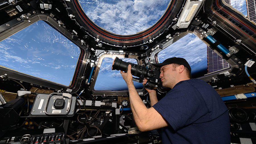 Astronaut Matthew Dominick points his camera out a window on the cupola as the space station orbited above the Atlantic Ocean off the coast of Africa.