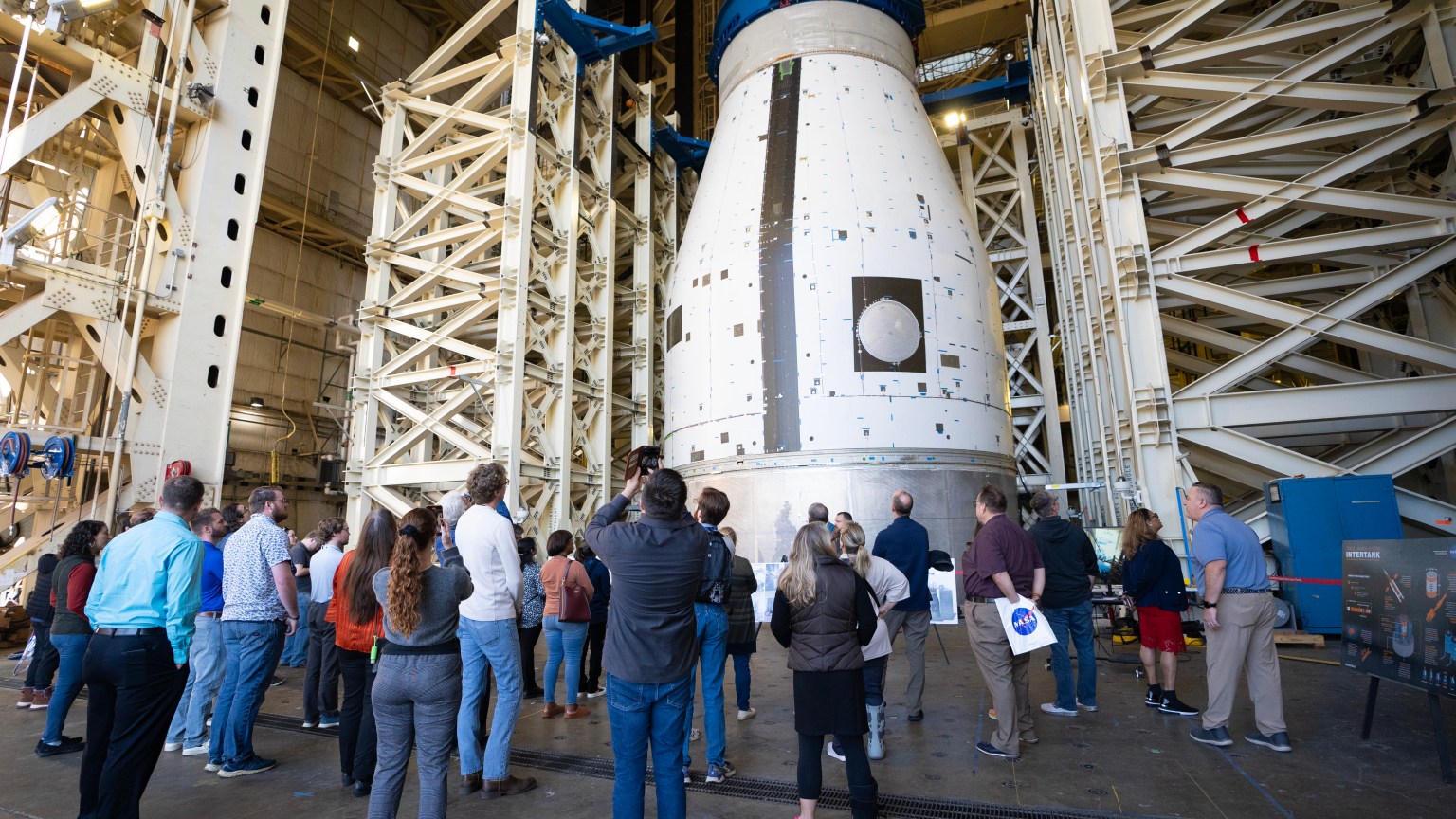 A group of Marshall team members gather below the development test article for the universal stage adapter that will be used on the second variant of SLS, called Block 1B. The universal stage adapter is located inside one of the high bays in building 4619. The universal stage adapter will connect the Orion spacecraft to the SLS exploration upper stage. With the exploration upper stage, which will be powered by four RL10-C3 engines, SLS will be capable of lifting more than 105 metric tons (231,000 pounds) from Earth's surface. This extra mass capability enables SLS to send multiple large payloads to the Moon on the same launch.