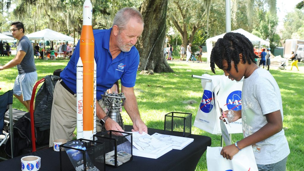 NASA representative Lacy Thompson helps an event-goer with coloring sheets