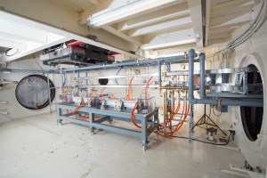 A large room with a testing rig surrounded by various wires, cables, and hardware for electrified aircraft propulsion system testing.