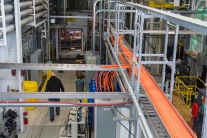 A man walks inside a large test room surrounded by hardware, cables, and metal equipment.