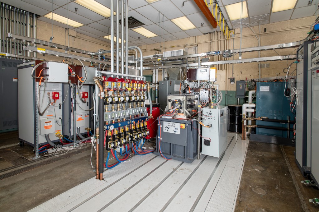 A room full of various test equipment, including gauges, cables, and machinery, with a rectangular motor drive stand in the center.