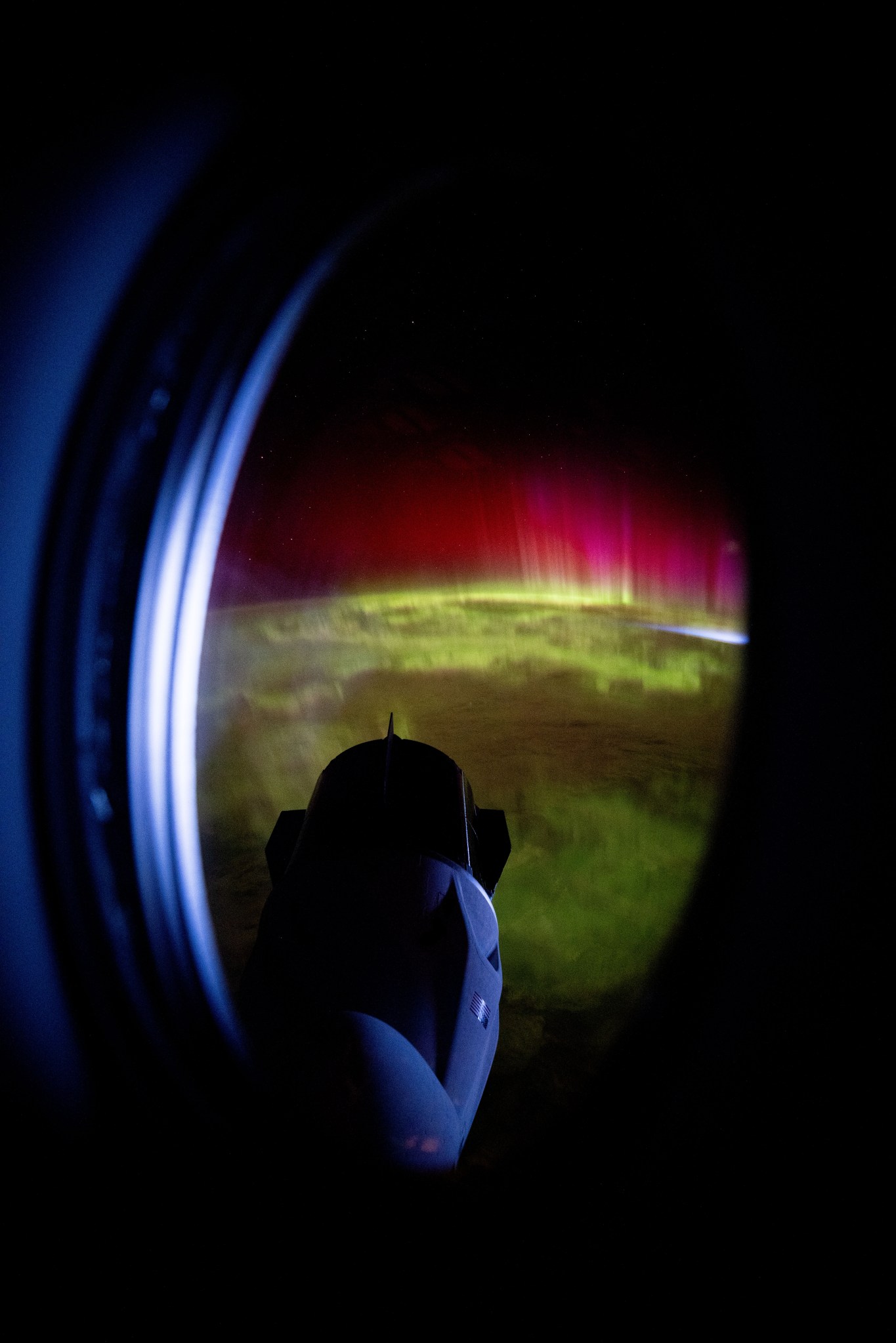 iss072e031823 (Oct. 7, 2024) -- Peering through the window of the SpaceX Dragon Endeavour spacecraft, NASA astronaut Matthew Dominick captured this image of the SpaceX Dragon Freedom spacecraft as vivid green and pink aurora swirled through Earth's atmosphere while the International Space Station soared 273 miles above the Indian Ocean.