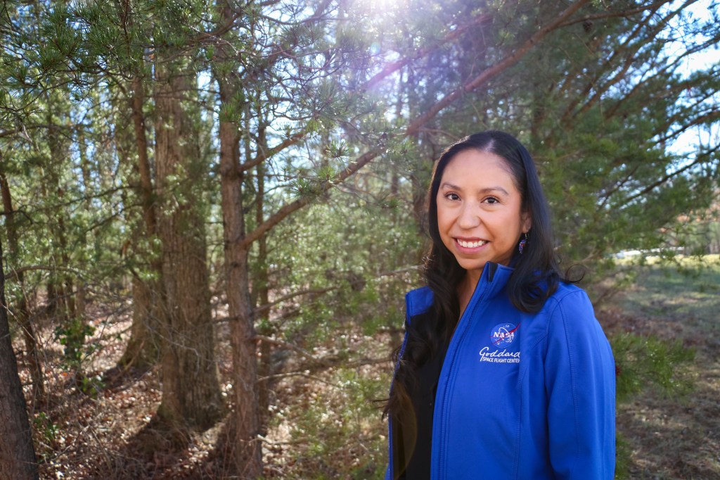 Miranda Meyer, a Native American woman, poses for a portrait among trees.