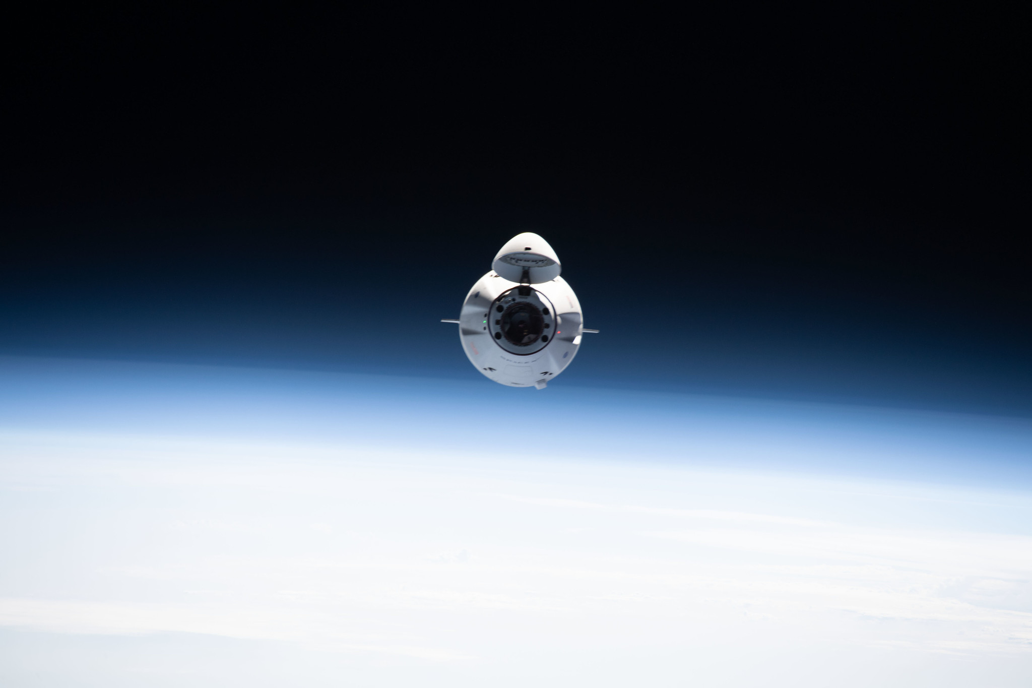 A white spacecraft floats in space above the Earth.