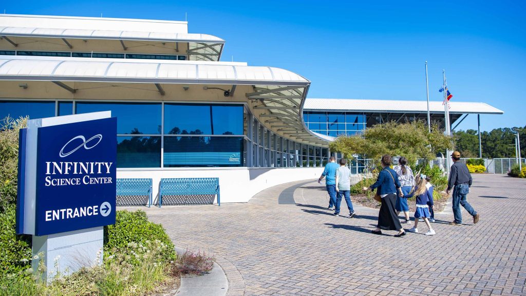 visitors to INFINITY Science Center are shown walking towards the museum's entrance