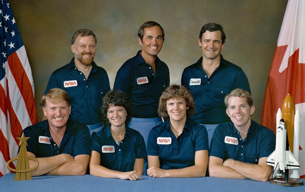 The STS-41G crew of Jon A. McBride, front row left, Sally K. Ride, Kathryn D. Sullivan, and David C. Leestma; Paul D. Scully-Power, back row left, Robert L. Crippen, and Marc Garneau of Canada