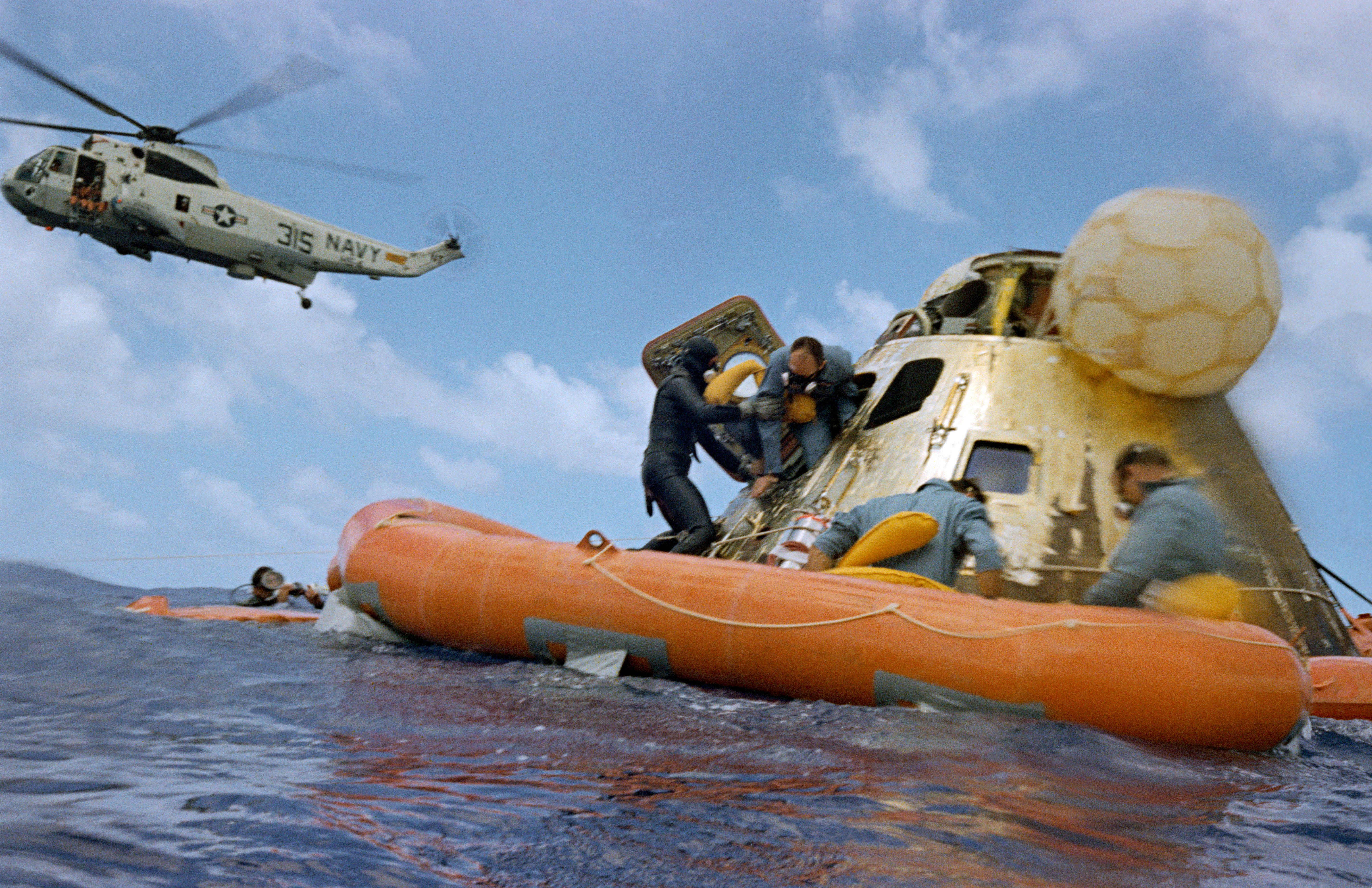 Image taken by a recovery diver of the decontamination officer assisting Alan L. Bean out of Yankee Clipper, with Richard F. Gordon, left, and Charles 