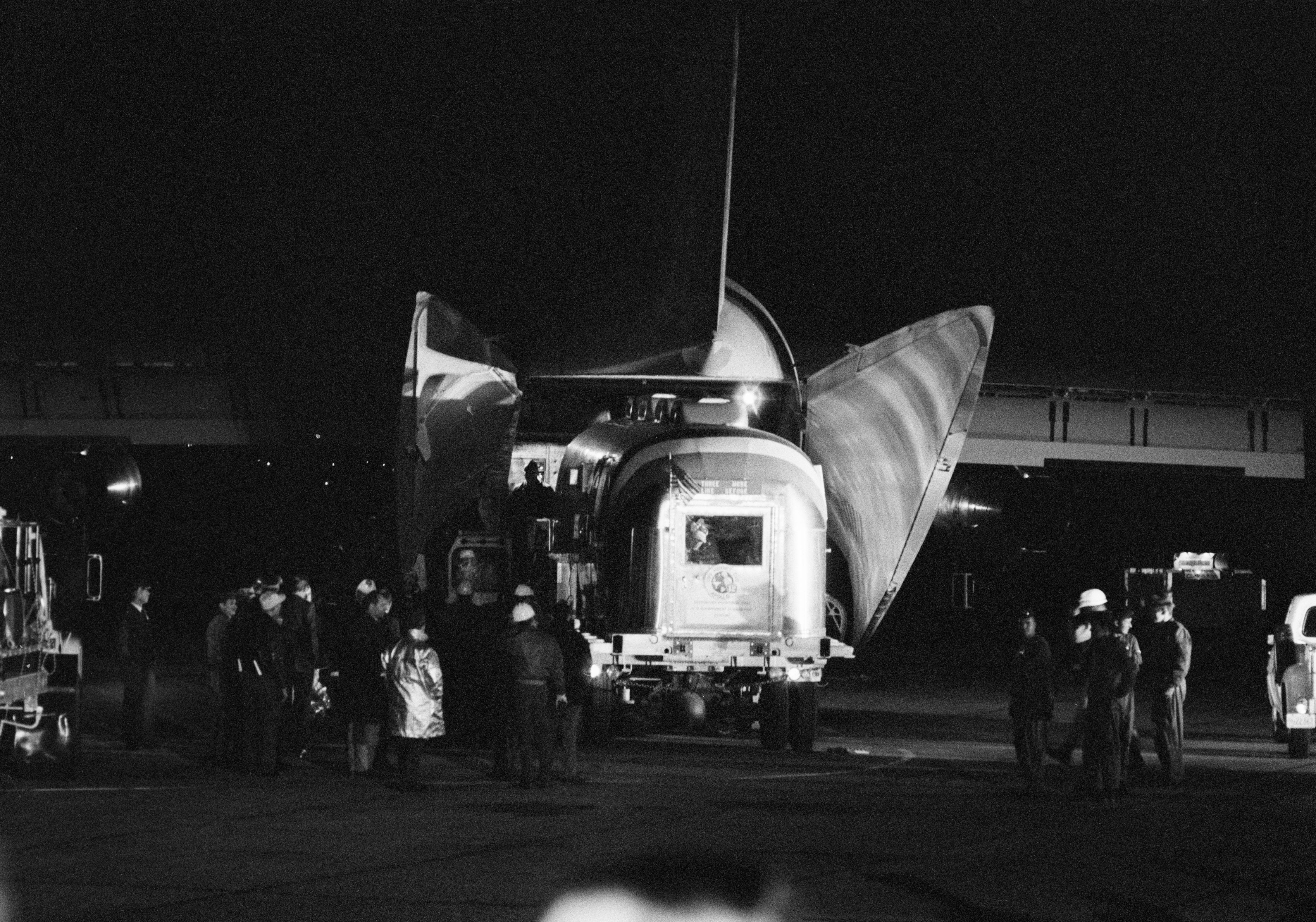 Workers at Ellington Air Force Base in Houston offload the MQF with the astronauts inside