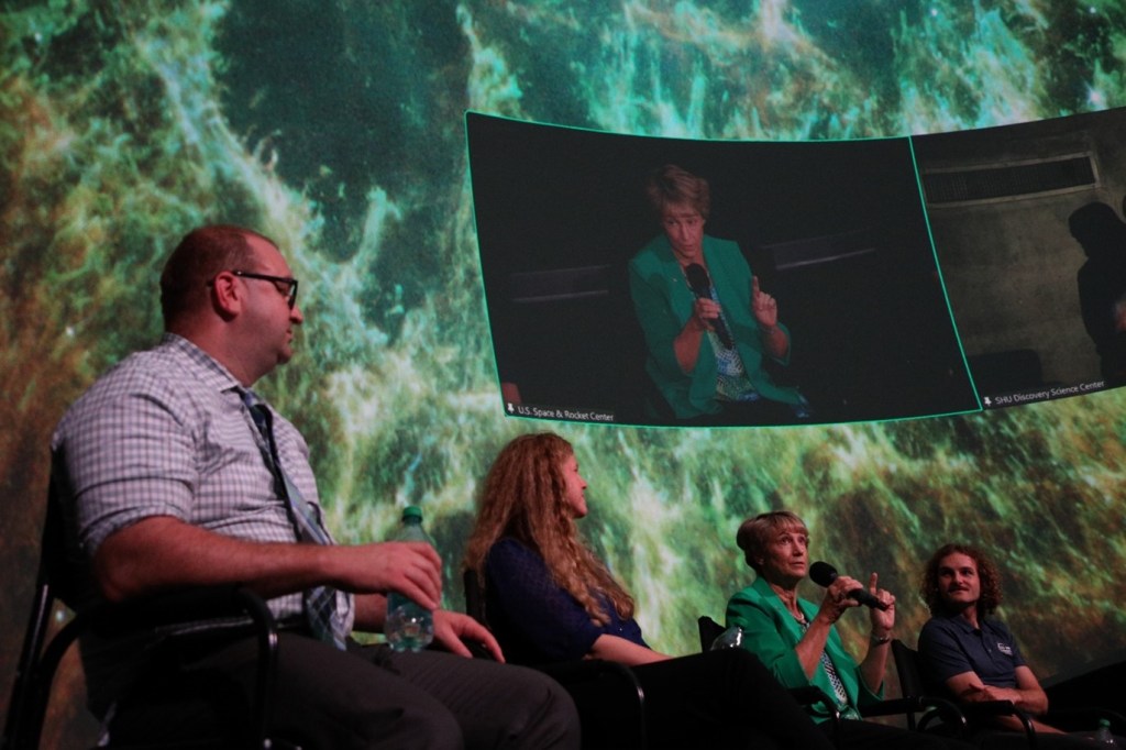 A photo of the Chandra team with an astronaut on the screen behind them.