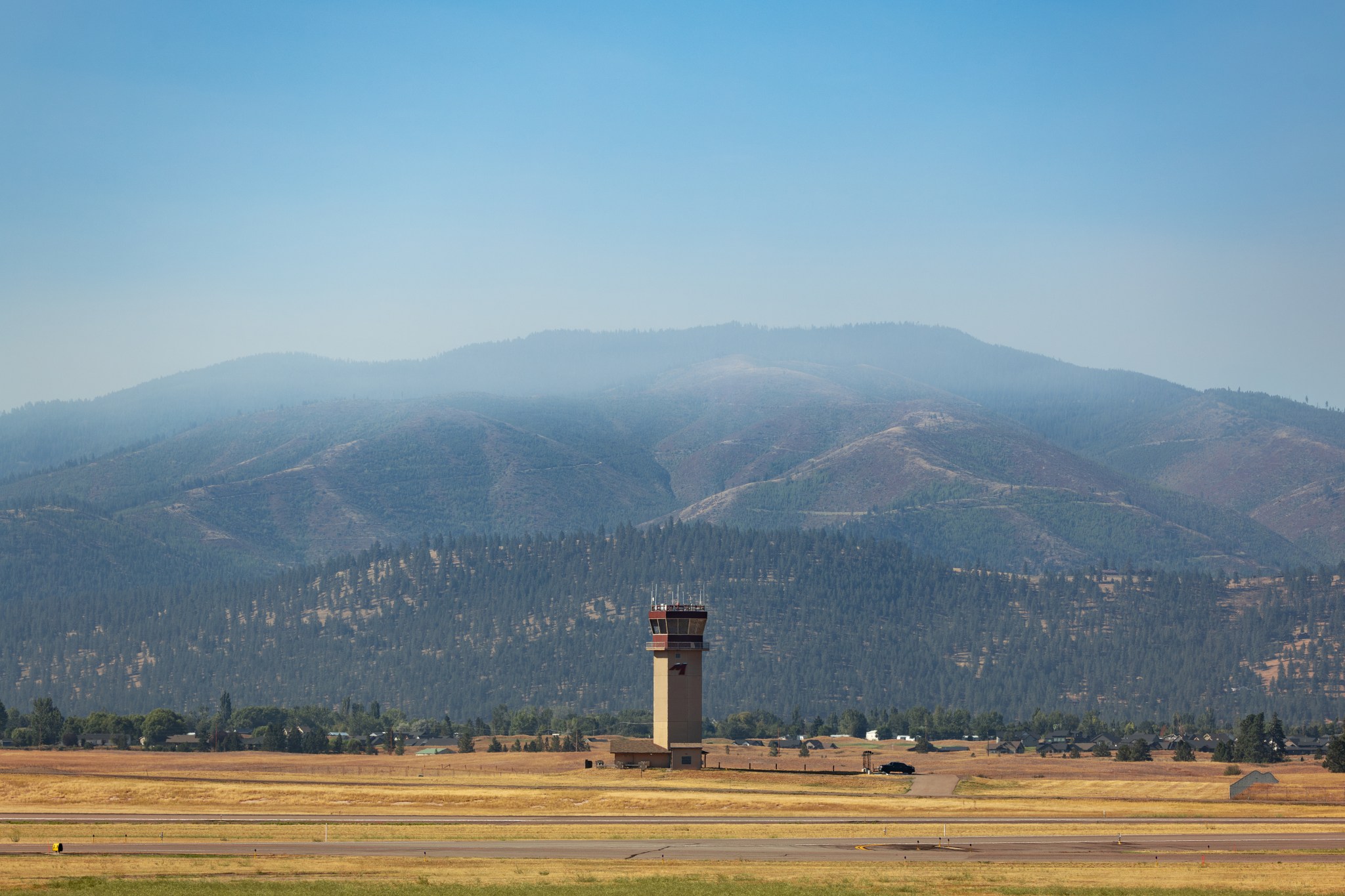 Smoke from the nearby Miller Peak Fire drifts by the air control tower at Missoula Montana Airport on August 29, 2024. Miller Peak was one of several fires burning in and around Missoula that month, creating a smoke-impacted environment which, combined with the mountainous terrain, makes traditional forecasting methods difficult: a problem the FireSense team is working to solve.