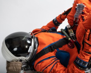 A spacesuit engineer tests the OCSS suit in a seat mock up. Credit: NASA/Bill Stafford