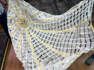 2)A top view of the Pilot parachute canopy. This is a Nylon (white) and Kevlar (yellow) ribbon parachute. Note the holes, known as geometric porosity, which are used to get the desired balance of drag and stability in the canopy. Credit: Courtney Beasley/Jared Daum