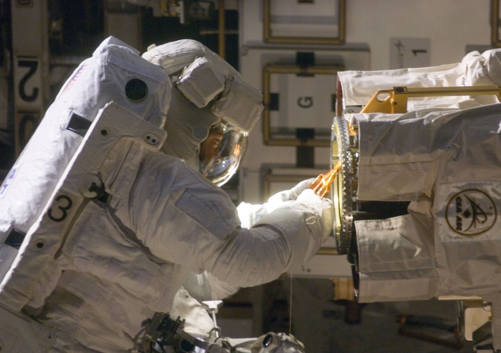 Robert “Bobby” L. Satcher lubricates the robotic arm’s Latching End Effector