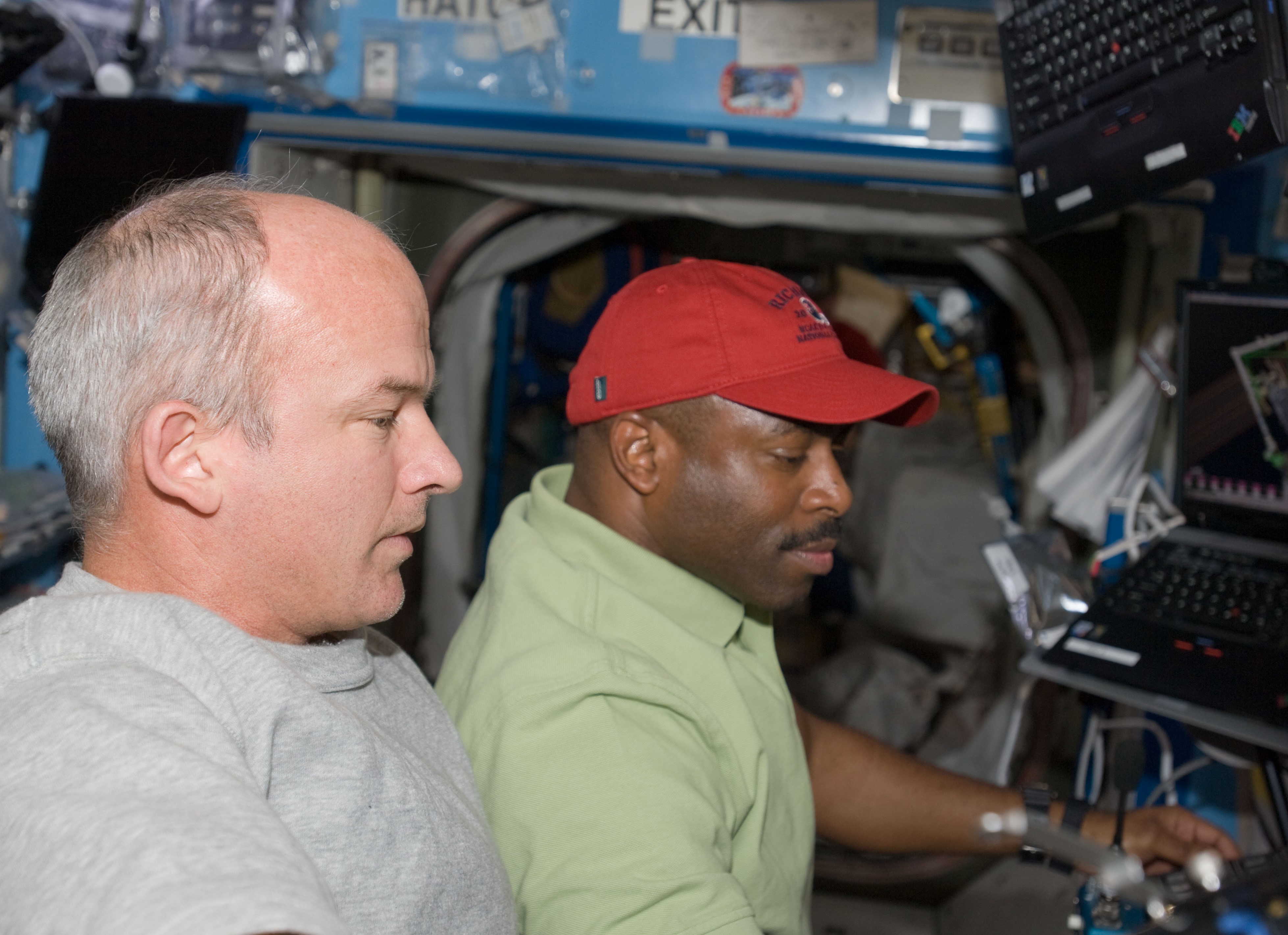 Space station crew member Jeffery N. Williams assists STS-129 astronaut Leland D. Melvin in operating the space station’s robotic arm