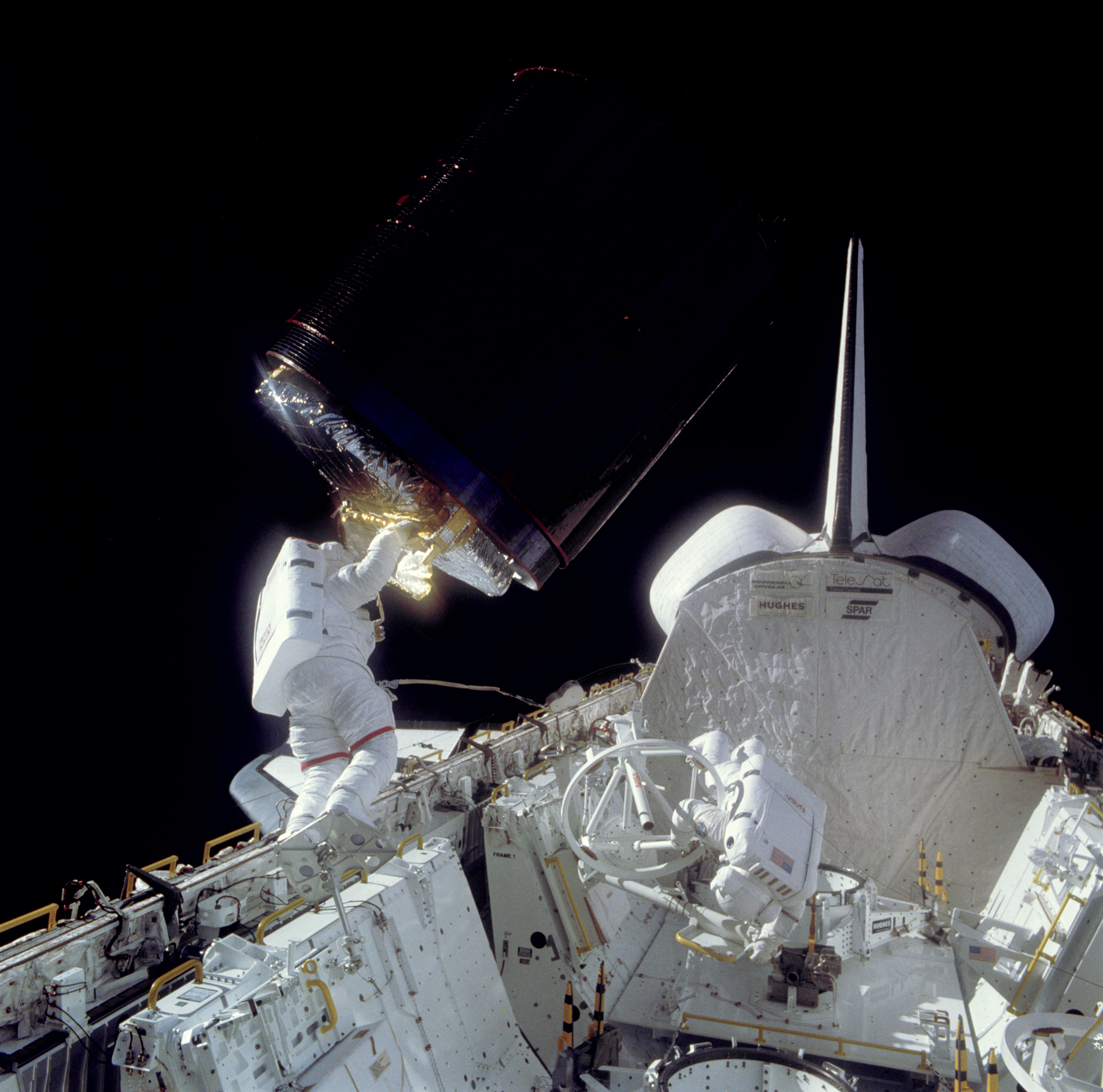 Allen, left, and Dale A. Gardner prepare to place Palapa in its cradle in the payload bay