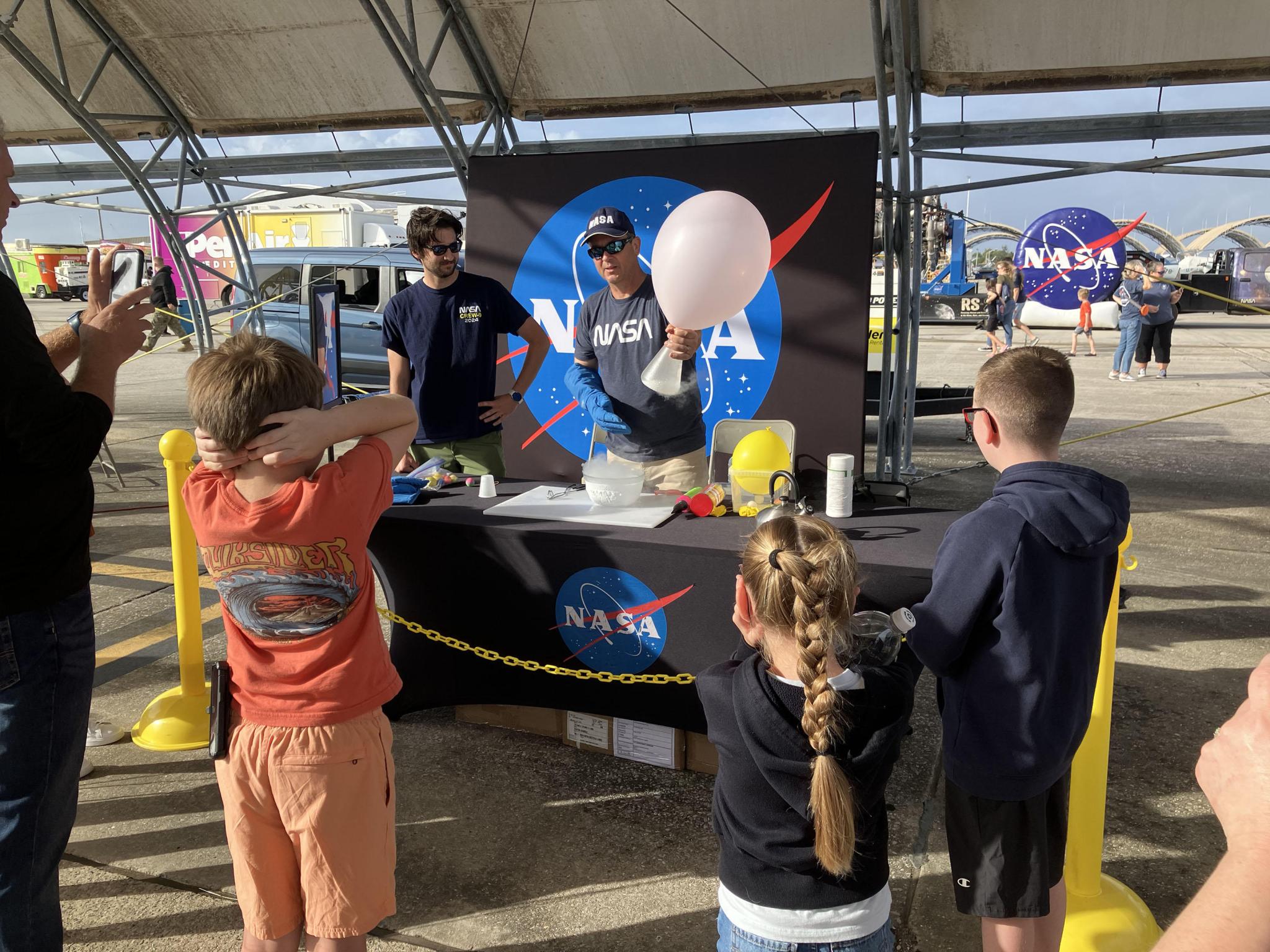 a few young air show attendees observing a demonstration by NASA Stennis representatives