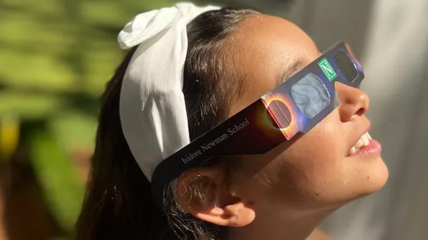 a young child wearing solar eclipse glasses looking up