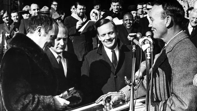 Four men, including the Prime Minister of Canada and the Apollo 11 astronauts standing outside exchanging gifts.