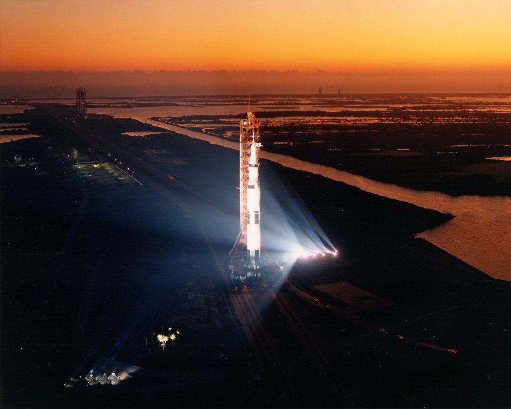 A large white rocket against an orange sunrise lit sky