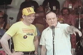 Two men, Neil Armstrong and Bob Hope, stand at a microphone, addressing a crowd.