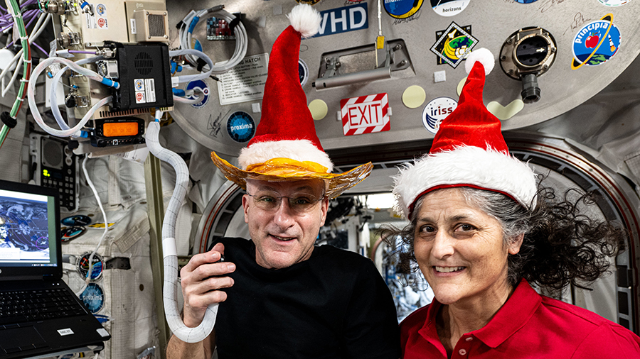 NASA astronauts Don Pettit and Suni Williams pose for a fun holiday season portrait while speaking on a ham radio inside the Columbus laboratory module.