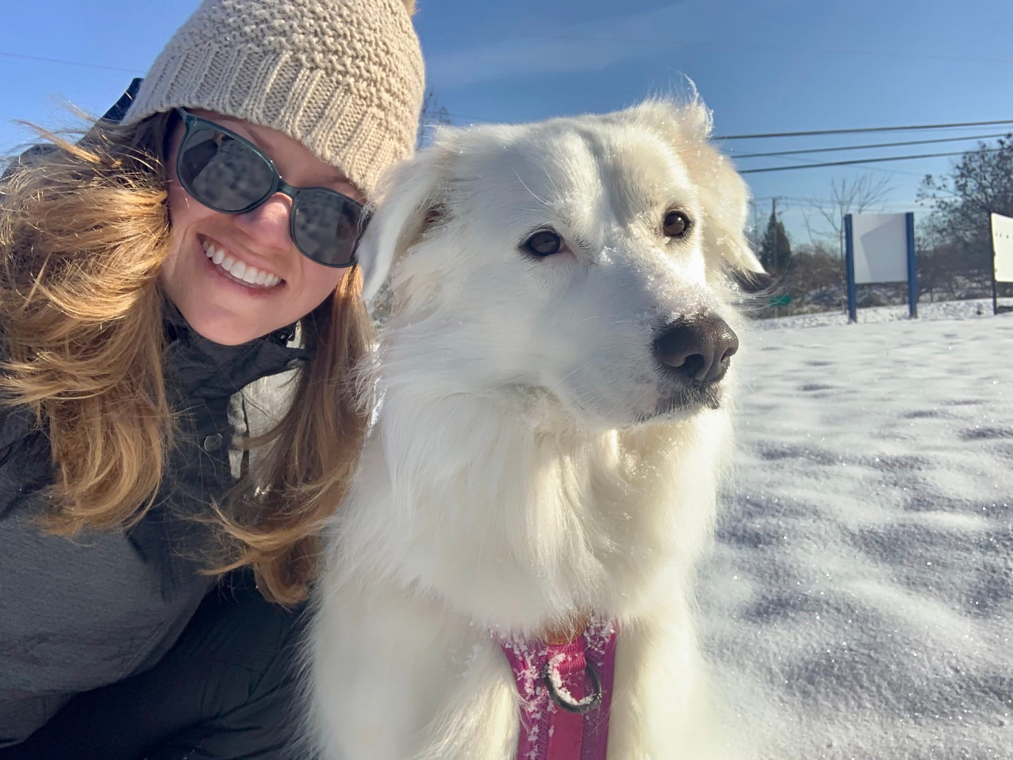 Sarah Peacock hugs a white dog in the snow.