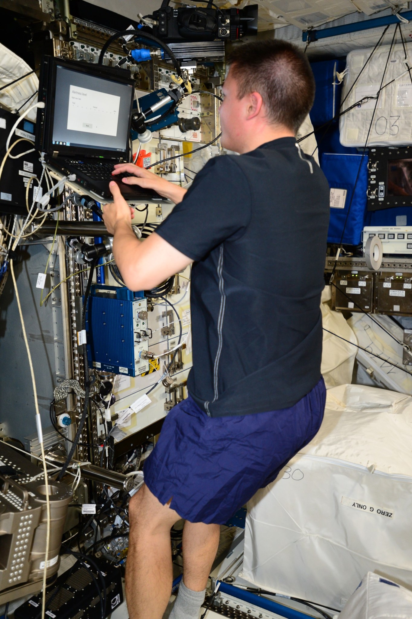 A NASA astronaut works on a laptop aboard the International Space Station.