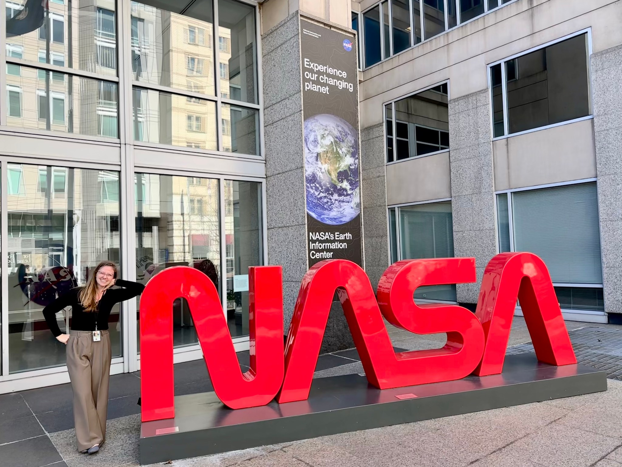 Sarah Peacock stands next to the worm logo at NASA Headquarters.