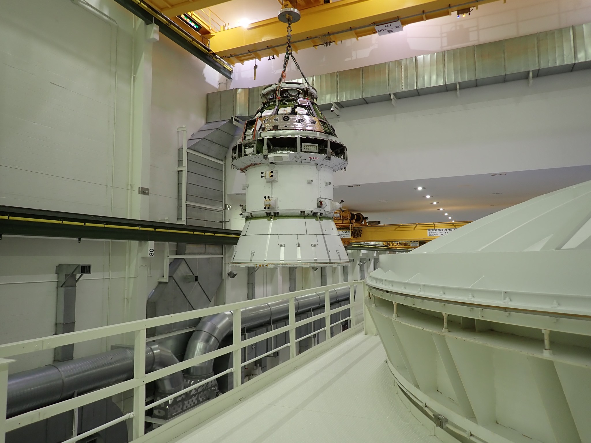 The Artemis II Orion spacecraft hoisted by a crane inside the Neil A. Armstrong Operations and Checkout building at NASA's Kennedy Space Center in Florida.