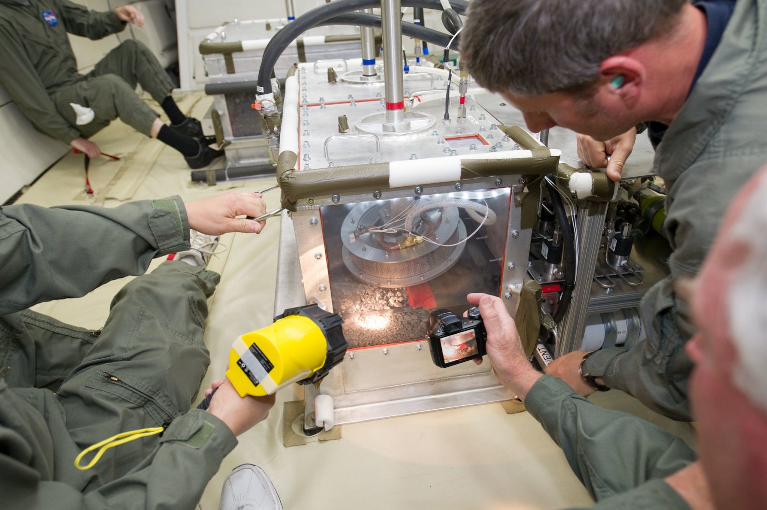 Two researchers study their experiment on a parabolic jet.