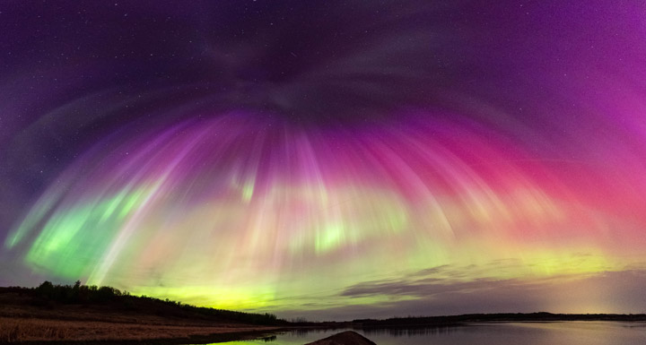 Colorful aurora in hues of green, yellow, purple, and pink seem to cascade over the landscape near Saskatoon in Saskatchewan, Canada