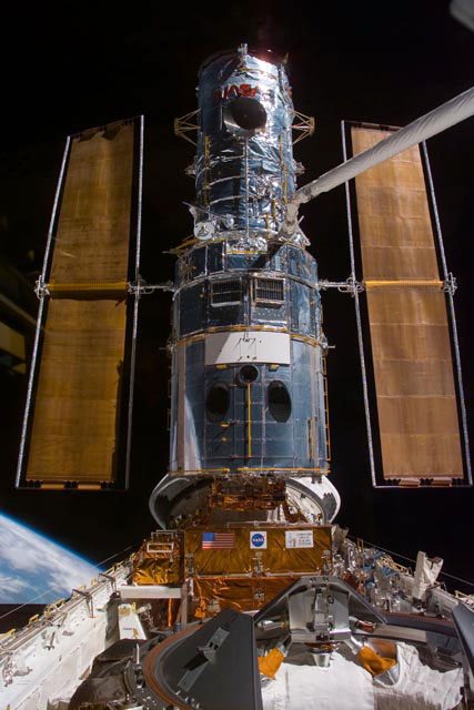 The Hubble Space Telescope attached to the space shuttle, with a black sky background