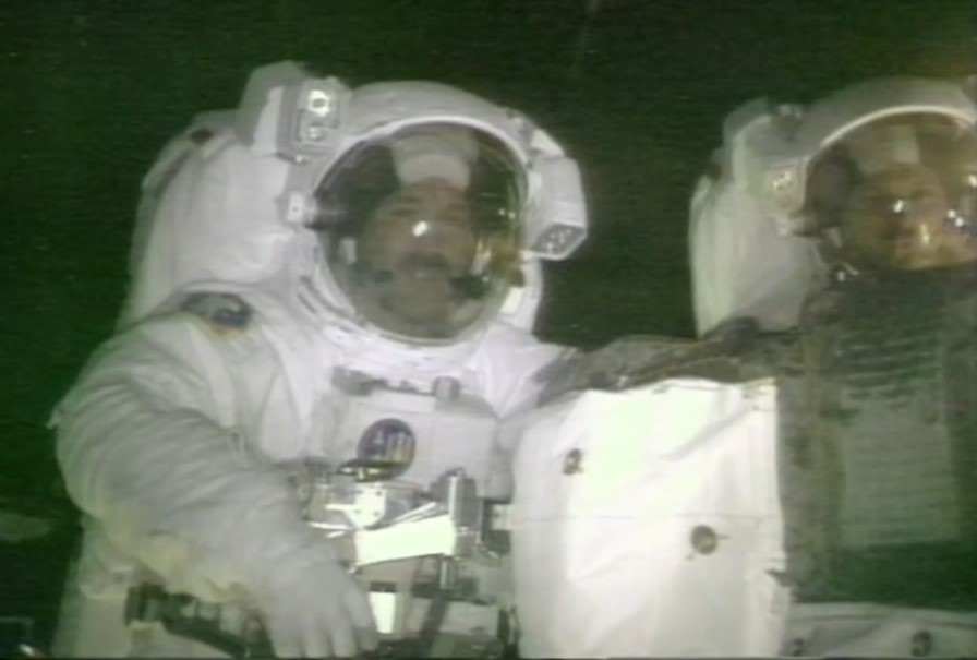 Two astronauts in white spacesuits facing the camera