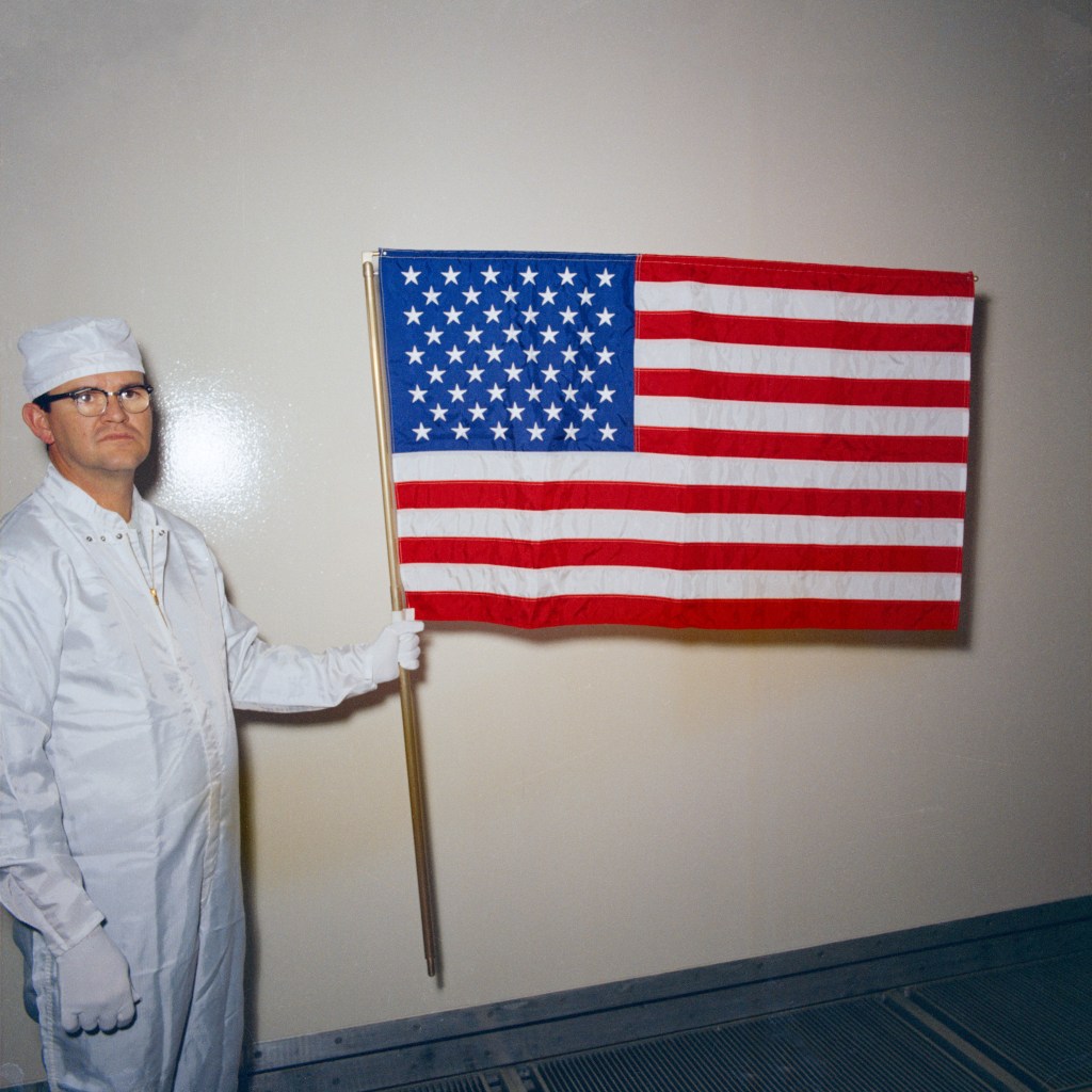 A white clad technician holding an American flag.