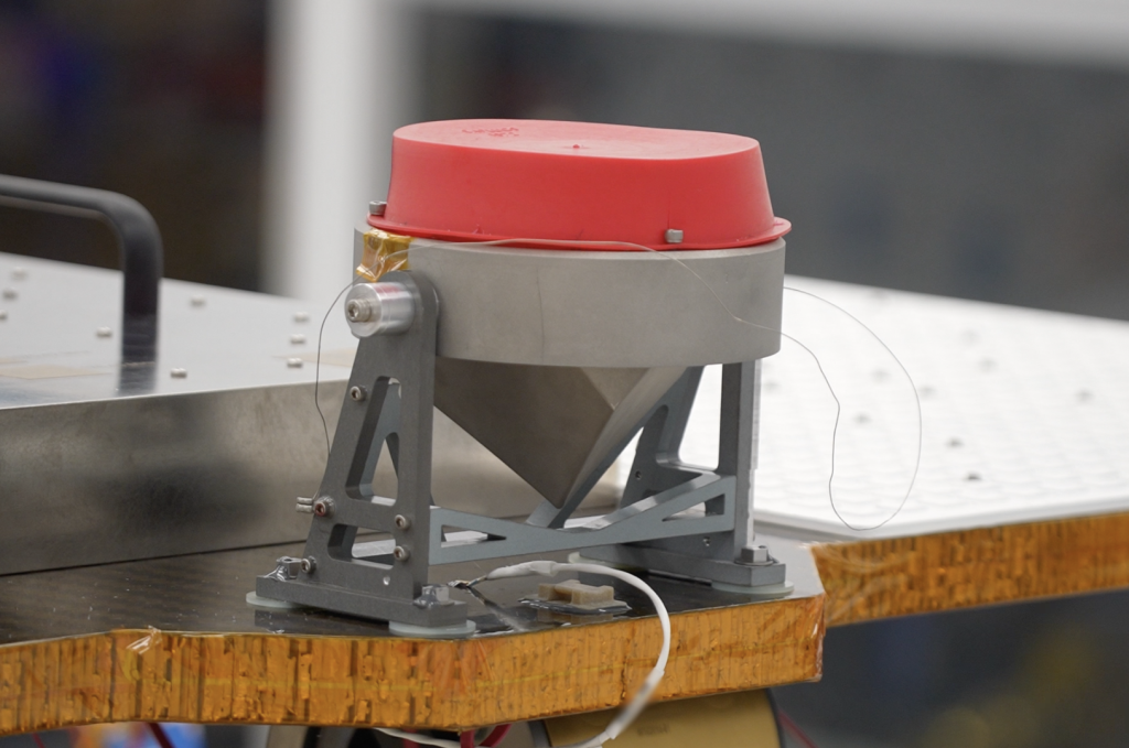 A close up shot of the payload that has a large red top with a gray cone.