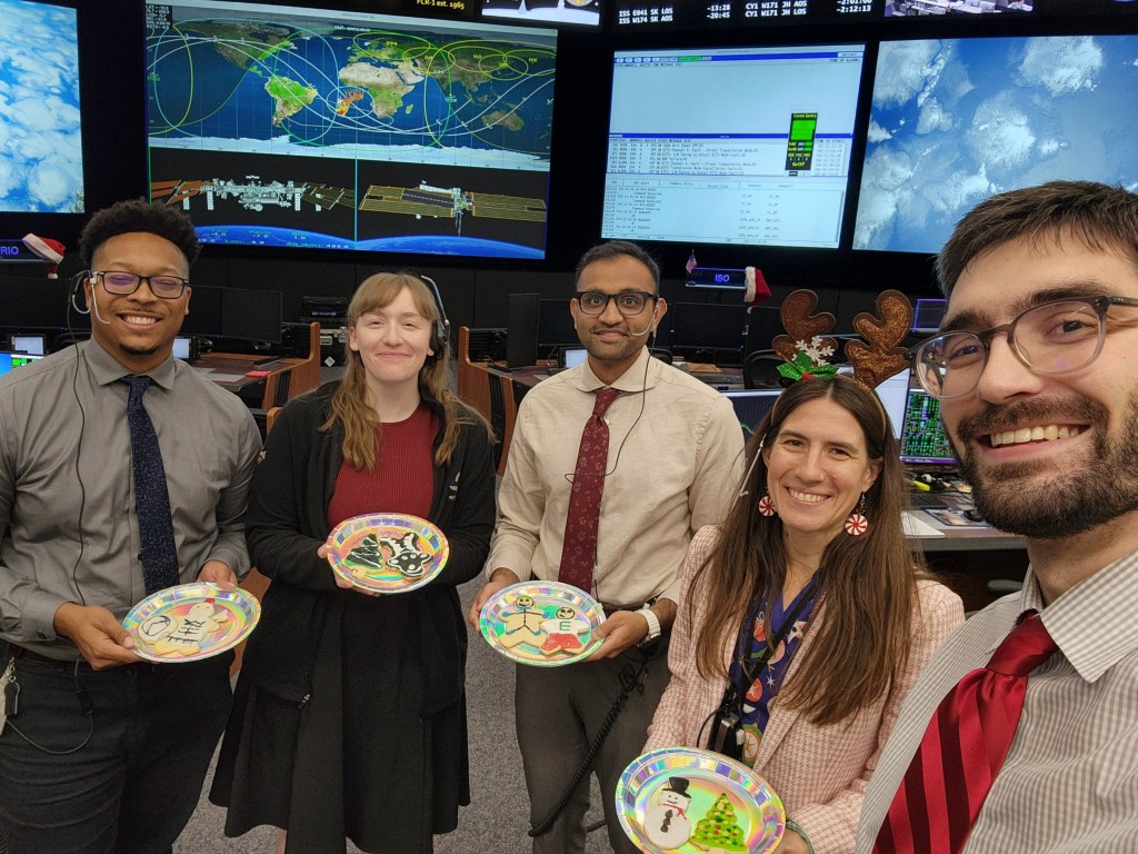 MCC Orbit 1 team members pose with decorated holiday cookies.