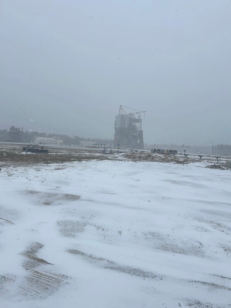 a test stand is shown in the background across a field of fresh snow