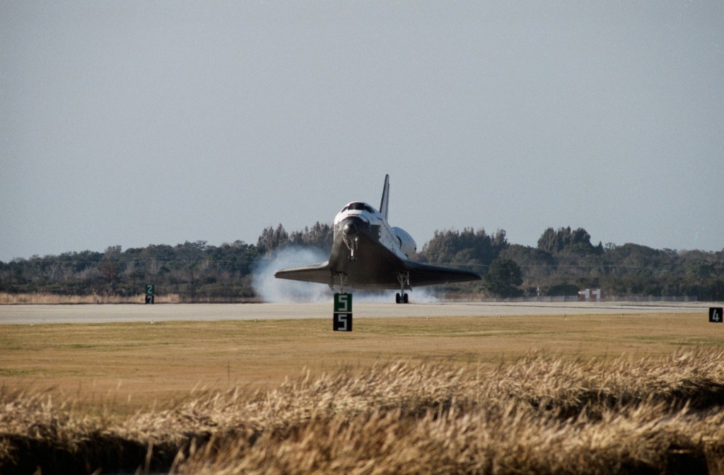 Image of space shuttle touching down on a runway.