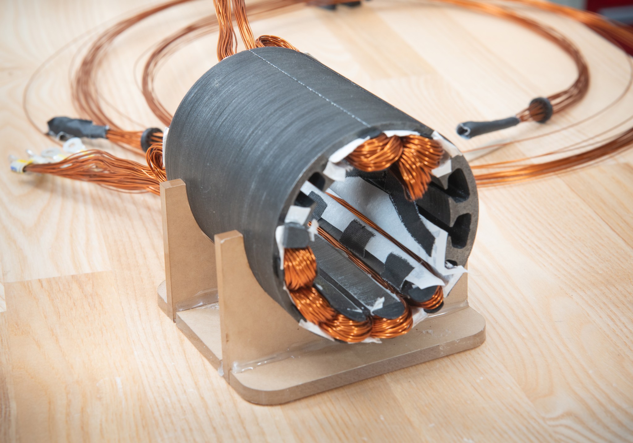 A close-up shot of a hollow metal cylinder with several thin copper-colored wires feeding through the inner wall.