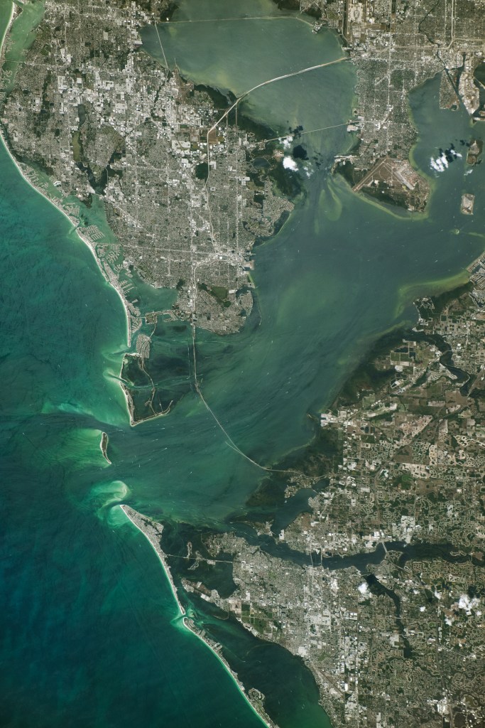 An astronaut aboard the International Space Station took this photograph of Tampa Bay, located along the west-central coast of Florida. It is the state’s largest open-water estuary, covering approximately 400 square miles (1,000 square kilometers). The photo shows the expanse of the bay, its connection to the Gulf of Mexico, and the surrounding urbanized land.