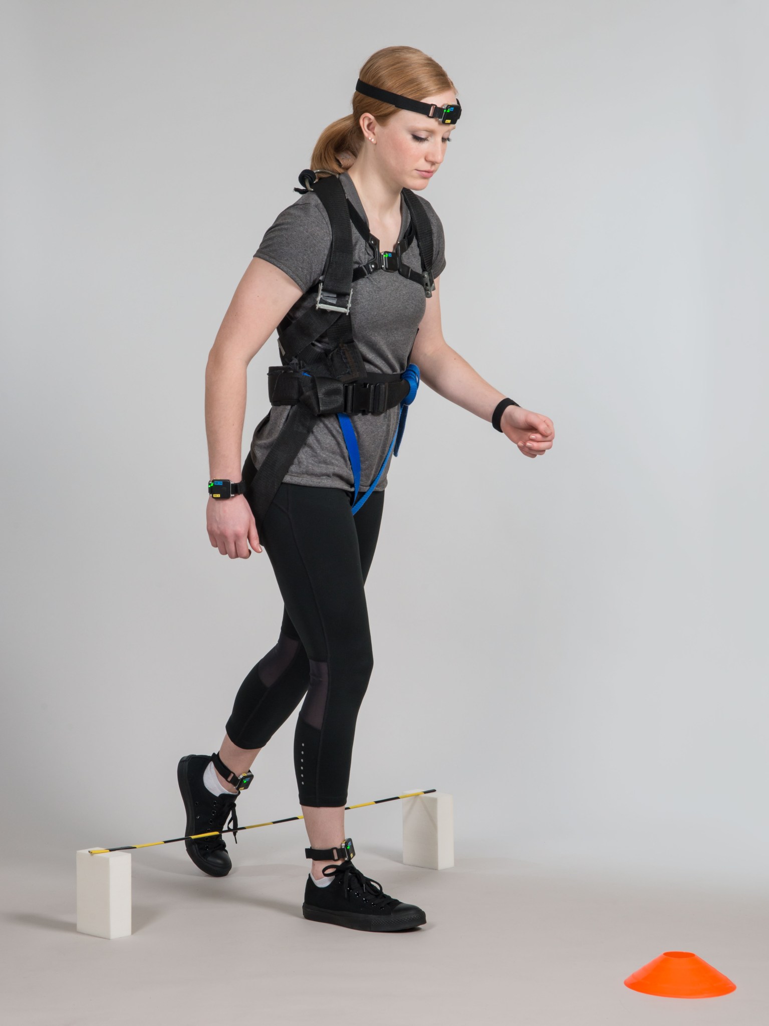 A woman wearing a gray t-shirt, black leggings, and black sneakers participates in a mobility test.