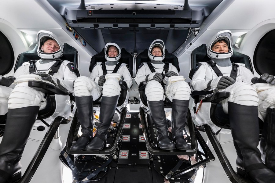 Image shows four astronauts in spacesuits inside the SpaceX Dragon spacecraft