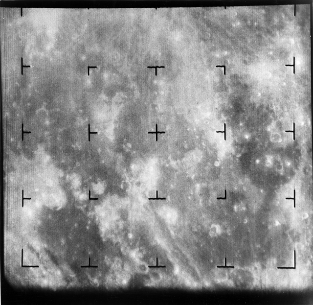 Black and white slightly blurry image of the Moon's surface with a few craters visible.