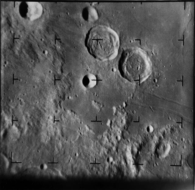 Black and white image of the Moon's surface, showing two large craters, several medium sized ones, and many smaller ones.